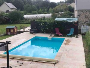 a swimming pool in a yard with two chairs at Villa avec Piscine in Brive-la-Gaillarde