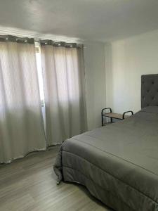 a bedroom with a bed and two windows with curtains at Lajes guests house in Lajes