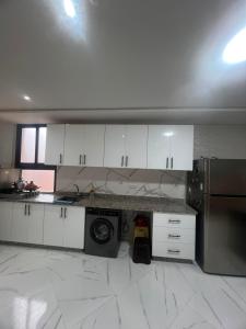 a kitchen with white cabinets and a washing machine at best standing with ascenceur in El Jadida