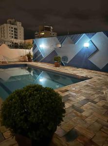 a swimming pool at night with lights on a building at Apartamento Saint Moritz flat service in São Bernardo do Campo