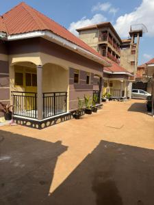 a small house with a balcony and a building at Crown Motel Lugala in Kampala