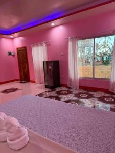 a pink bedroom with a bed and a window at Tellos Beach House in Siquijor