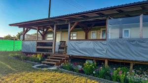a house with a covered porch and flowers at Motyl in Doba