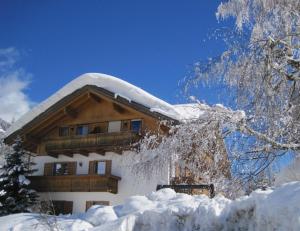 a house covered in snow in front of a mountain at Appartements Johann Bachmann in San Candido