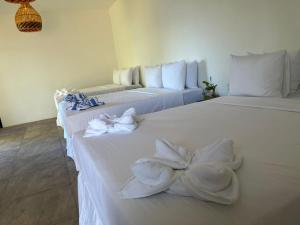 two white beds with towels on them in a room at Casa Bambú Hotel in Masaya