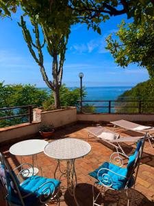 a patio with tables and chairs and a view of the ocean at Il Nido del Gabbiano in Vietri sul Mare