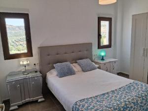 a bedroom with a large bed with two windows at Atalaya de los Bermejales Villa privada piscina in Los Morales +26 photos