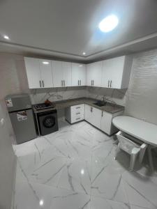 a kitchen with white cabinets and a marble floor at relaxtime avec ascenceur in El Jadida