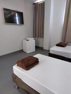 a bedroom with two beds with a brown blanket on it at Grande Hotel Havana - Hospedagem Econômica in Uberaba