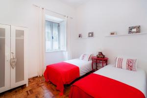 two beds in a room with red and white sheets at Casa da Avenida in Cascais