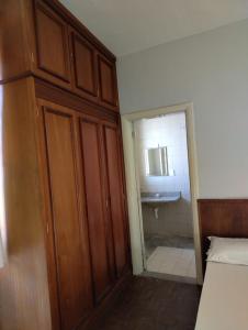 a bedroom with a wooden cabinet and a bathroom at Grande Hotel Havana - Hospedagem Econômica in Uberaba +6 photos