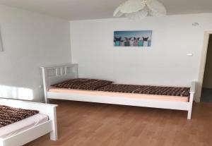 2 Betten in einem Zimmer mit weißen Wänden und Holzböden in der Unterkunft White House Bochum II in Bochum