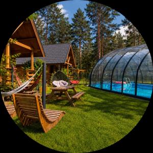 a backyard with a pool and a swing and a greenhouse at Lesne Runo Borsk, basen z podgrzewaną wodą in Borsk