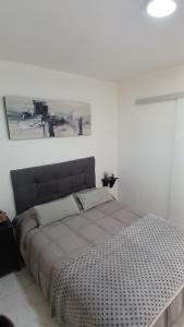 a bed in a white room with a picture on the wall at Marce's house in General Roca