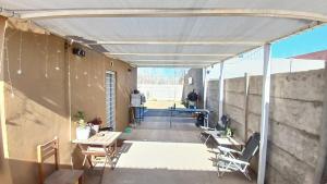 a patio with tables and chairs under a white canopy at Marce's house in General Roca