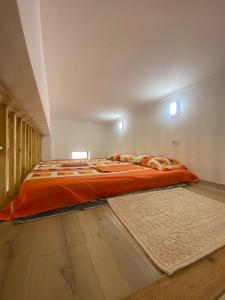 a large bed with an orange comforter in a bedroom at Pogradec Lake Apartments in Pogradec