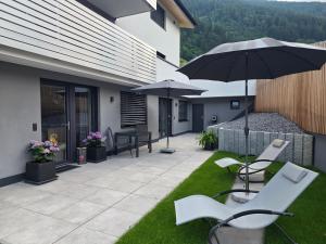 an outdoor patio with chairs and an umbrella at Mountainlights Apartment in Neustift im Stubaital