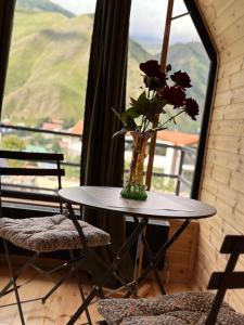 a vase of flowers on a table in a room with a window at Mountain Stories Kazbegi-Stepantsminda in Kazbegi