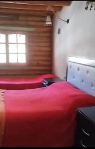 a bedroom with a red bed and a window at Cabañas Espacio Prana in Uspallata