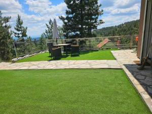 a patio with a table and chairs on the grass at Vila Ivona in Divčibare +15 photos