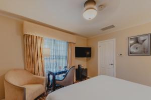 a hotel room with a bed and chairs and a window at Coast Village Inn in Santa Barbara