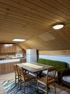 a dining room with a table and a green couch at Apartmán Gál 3 in Kvačany +14 photos