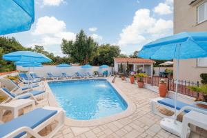 a swimming pool with chairs and umbrellas at Palmer Residence Krk in Dobrinj