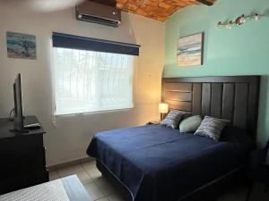 a bedroom with a blue bed and a window at "Le Petit Oasis" Pool, AC and Beach 1 minute away in La Peñita de Jaltemba