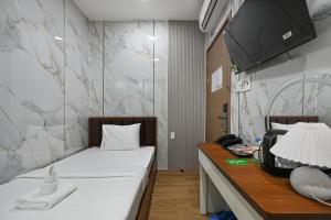 a room with a bed and a desk with a lamp at The Crown Airport Hotel in Ho Chi Minh City