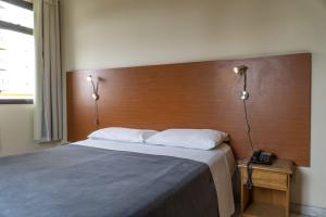 a bedroom with a large bed with a wooden headboard at Hotel Vila Rica Flat in Resende