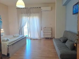 a bedroom with a couch and a bed and a window at Medoro Piazza Roma Rooms in Milazzo
