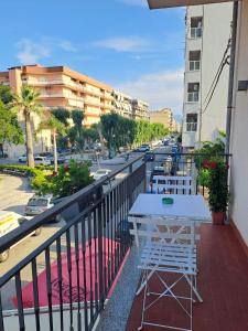 a balcony with a table and chairs and a street at Medoro Piazza Roma Rooms in Milazzo