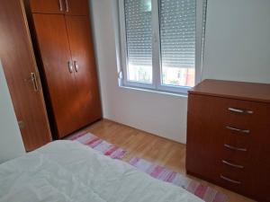 a bedroom with a bed and a dresser and two windows at Dama 1 in Bitola