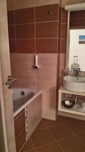La salle de bains est pourvue d'un lavabo, d'une baignoire et d'un miroir. dans l'établissement Apartmán Hory, à Štrbské Pleso