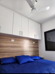a bedroom with a blue bed and white cabinets at Apto Sol Nascente in Mongaguá