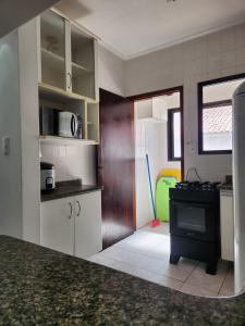 a kitchen with white cabinets and a black stove at Apto Sol Nascente in Mongaguá +14 photos