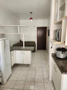 a kitchen with white cabinets and a tiled floor at Apto Sol Nascente in Mongaguá