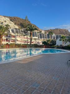 a swimming pool with palm trees and buildings in the background at Cura Marina in Playa del Cura