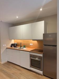 a kitchen with white cabinets and a stainless steel refrigerator at Le Col Getaway Virage 6 in Le Bourg-dʼOisans