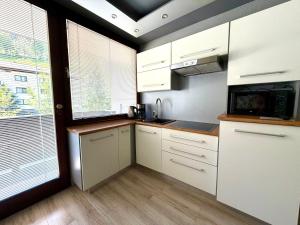 a small kitchen with white cabinets and a window at Apartment Essreithweg Kaprun by Jara in Kaprun