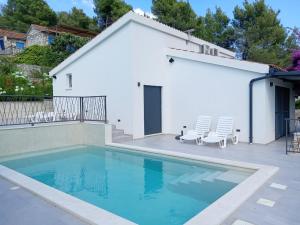 a swimming pool in front of a white house at Villa Mala Smišna Poolside Paradise by the Sea in Maslinica