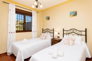 two beds in a room with two windows at Villa Las Palomas 2 in Nerja +9 photos
