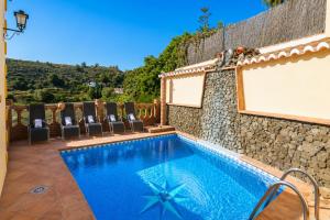 a swimming pool with chairs and a stone wall at Villa Las Palomas 2 in Nerja