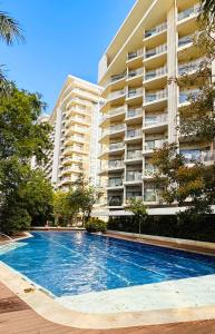 a swimming pool in front of a large building at Resort Living 1BR Corner Apartment with Balcony in Maribago