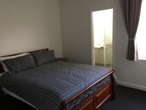 a bedroom with a bed with a blue checked comforter and a window at Falcon Bay 4x4 Townhouse in Wannanup