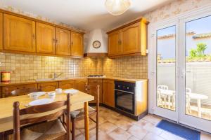 a kitchen with wooden cabinets and a wooden table with chairs at La Brise de Valras in Valras-Plage