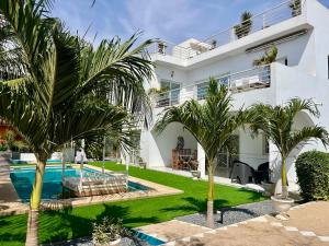 a villa with a swimming pool and palm trees at KEUR MATY Charmante et Moderne Villa 5 chambres, 5 salles de bains à Warang in Ouoran