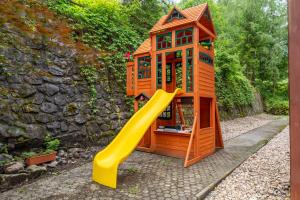 a wooden play house with a yellow slide at Hotel Velveta in Špindlerův Mlýn