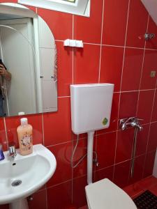 a red bathroom with a toilet and a sink at Dama 3 in Vojnica