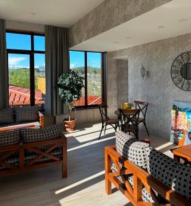 a living room with couches and a table and windows at Hotel Legiandro Surami in Surami